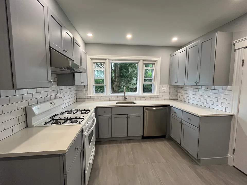 Newly renovated kitchen with new kitchen cabinets, quartz countertops, tile floors and backsplash, new electrical work and plumbing, and recessed lighting