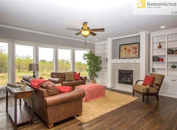 GREAT ROOM WITH WOOD FLOOR AND WALL OF WINDOWS, BOOKSHELVES AND FIREPLACE