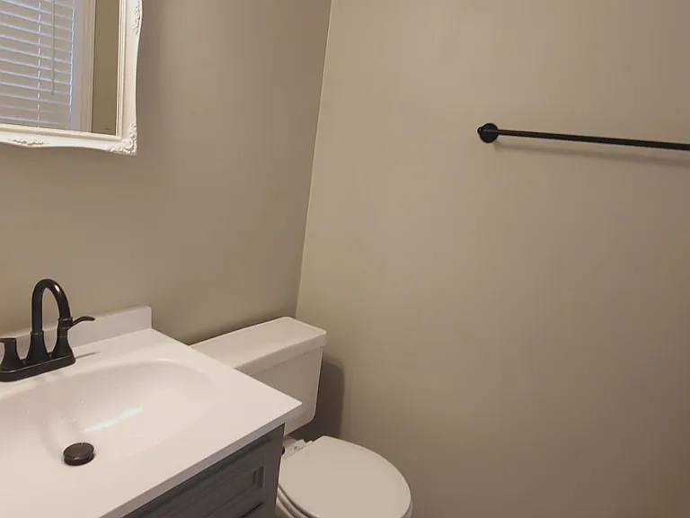Half bath off of the primary bedroom with tile floors, vanity, medicine cabinet.