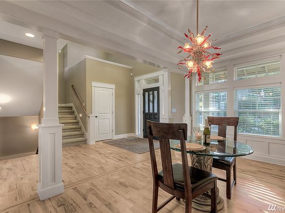 Formal dining room features double tray ceiling with crown molding and accent lighting, wainscoting, decorative pillars, pocket door with access to the kitchen and hardwood floors. 