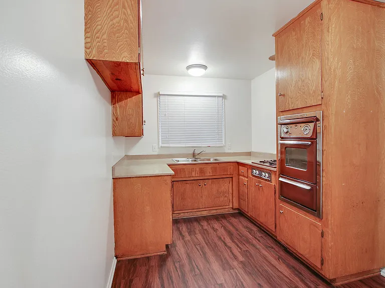 Kitchen with stainless steel Microwave oven, gas cooktop, quartz countertops, wood kitchen cabinets, and wood-inspired flooring