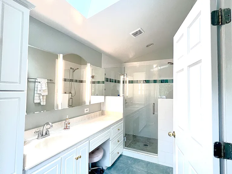 Primary bathroom with ceiling fan, new shower door and faucet.