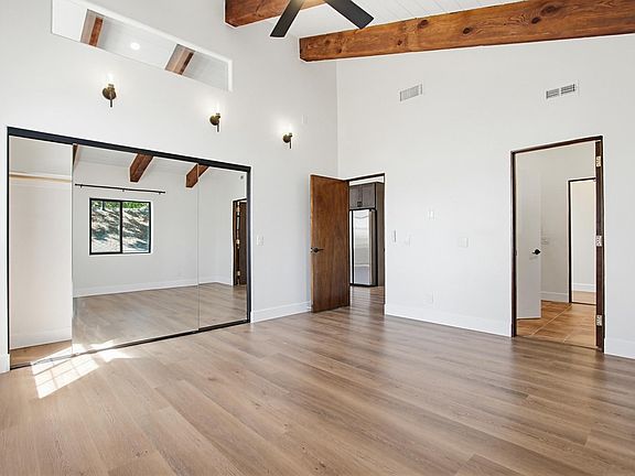 Bedroom 1 features wood beam vaulted ceiling, large closet, and upper window and sconces for aesthetic lighting. Jack and jill bathroom attached.