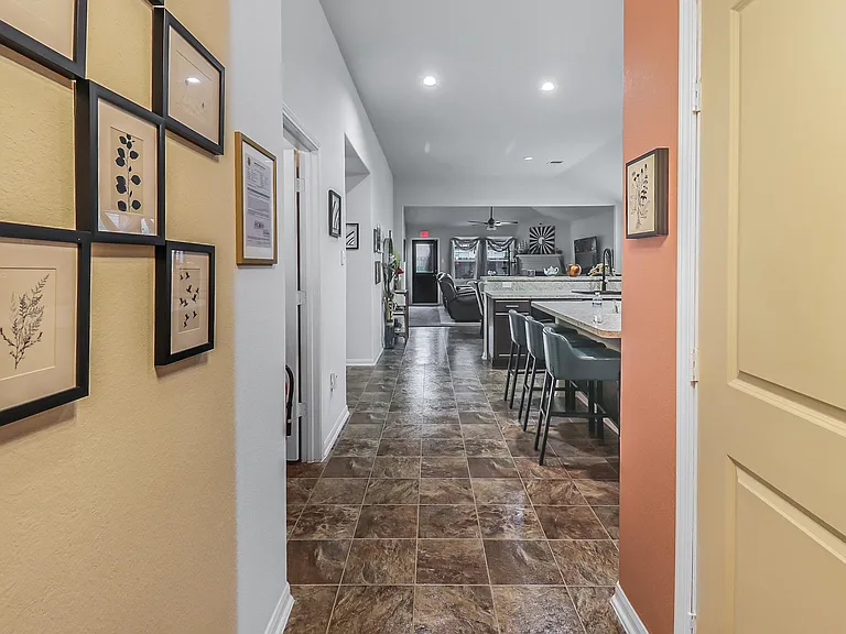 Open-concept kitchen and living area with a long breakfast bar, ample seating, and durable tile flooring throughout.