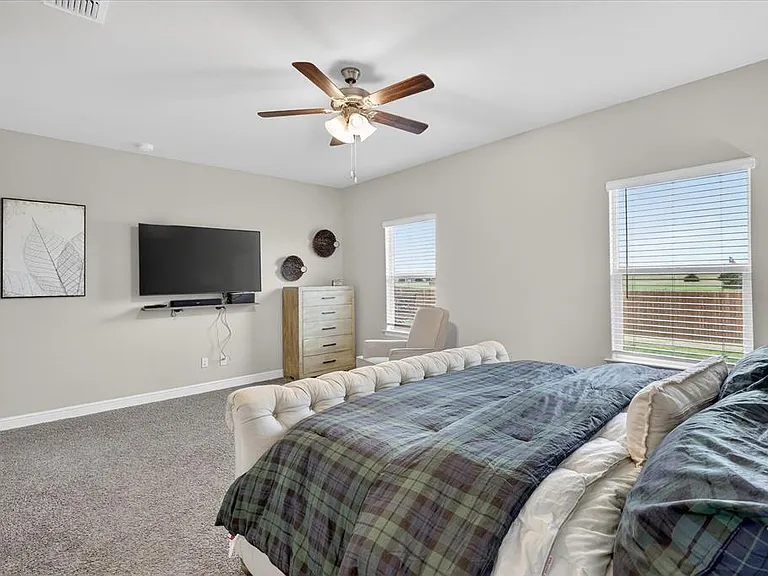 Carpeted bedroom with neutral wall tones and two windows featuring horizontal blinds