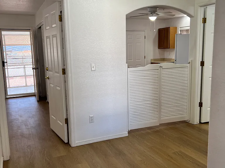 View from living room towards kitchen with saloon doors and bedroom (with door open to Arizona room)