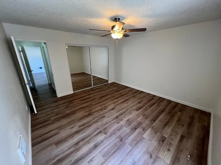 Downstairs guest bedroom standing at window looking down hallway toward the living room. 2x2