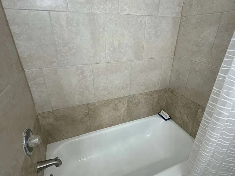 Tiled bathroom with full bathtub clean, functional, and well-maintained
