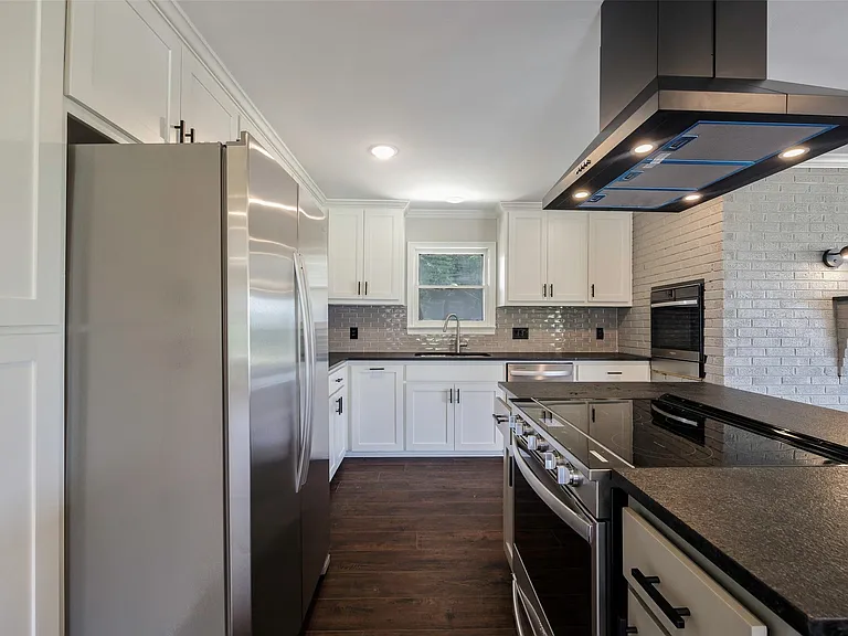Kitchen featuring backsplash, island range hood, ornamental molding, dark wood-type flooring, and appliances with stainless steel finishes