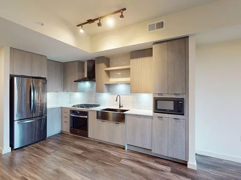 Apartment kitchen with black stainless steel appliances, quartz countertops, wood-style flooring, and custom Italian cabinetry.
