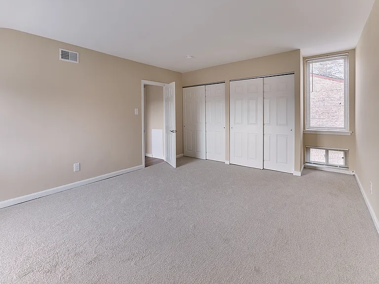 Spacious bedroom with dual closets and large window in this 2 Bed | 1.5 Bath, 989 sq. ft. home.