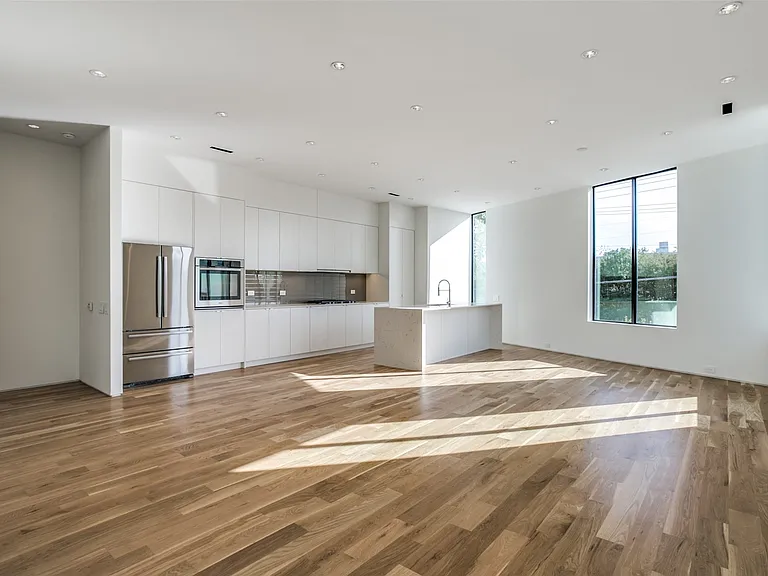 Open-concept living space featuring wood-finish flooring, recessed lighting, and contemporary white cabinetry