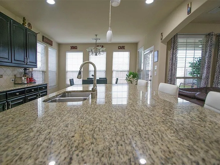 Kitchen featuring light granite countertops, tasteful backsplash, a healthy amount of sunlight, sink, and pendant lighting.