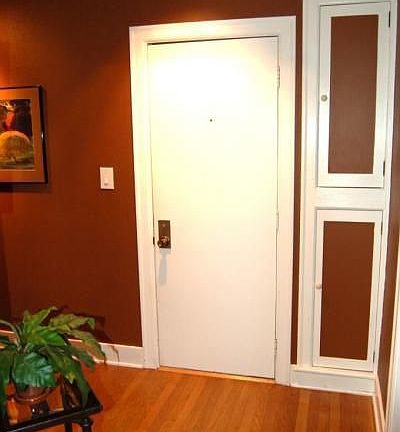 The entryway shows off beautiful floors, molding, and original cabinets