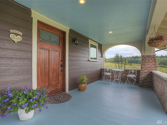 The elegant covered front porch with sky blue ceiling is a perfect spot to enjoy the countryside. Beautiful craftsman solid wood entry door. 
