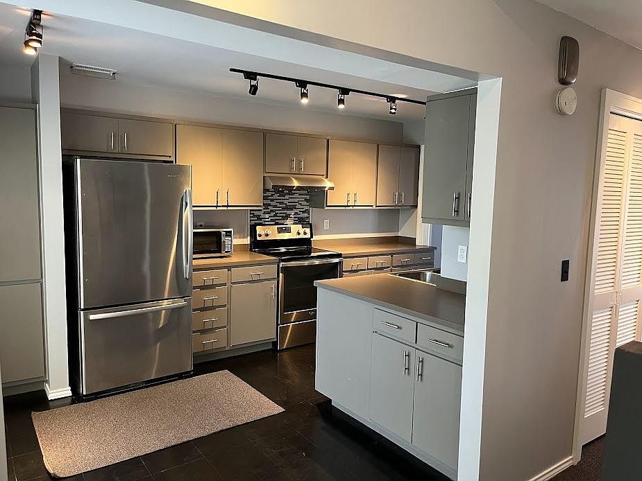 Entryway into dining/kitchen area showing high end kitchen appliances, micro wave, stove/oven. track LED lighting.