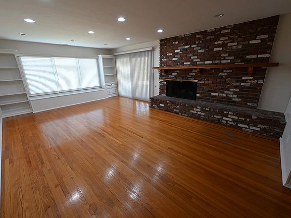 Living room with fireplace, mantle, built-in bookshelves, convenient storage under picture window.