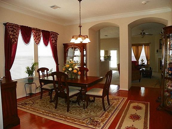 The formal dining room is grand with arched entry, hardwood floors,  and crown molding.