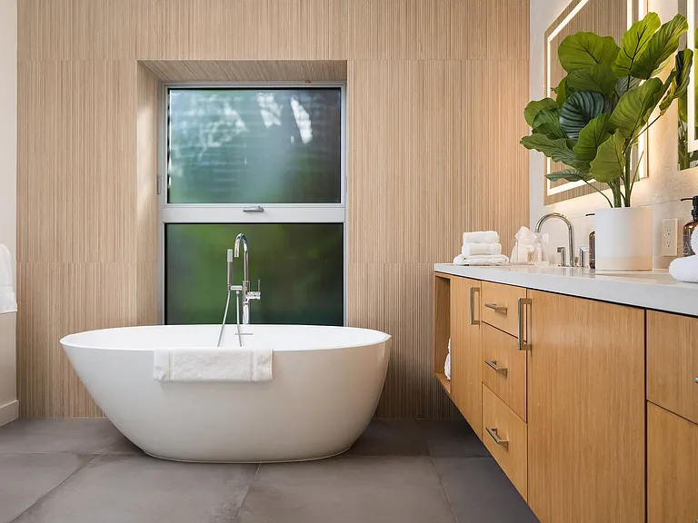 Primary bathroom with wooden touches, His & Hers sinks and a bathtub
