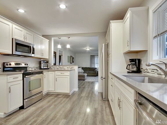 This kitchen is fabulous! Glass top stove/oven, microwave above, dishwasher, farmhouse single stainless steel sink, fridge has freezer on the bottom. Gray quartz counter tops with glass pencil tile is stunning! Tons of storage space in these custom built white cabinets. This is a kitchen for the gourmet cook in the house and a great gathering place.