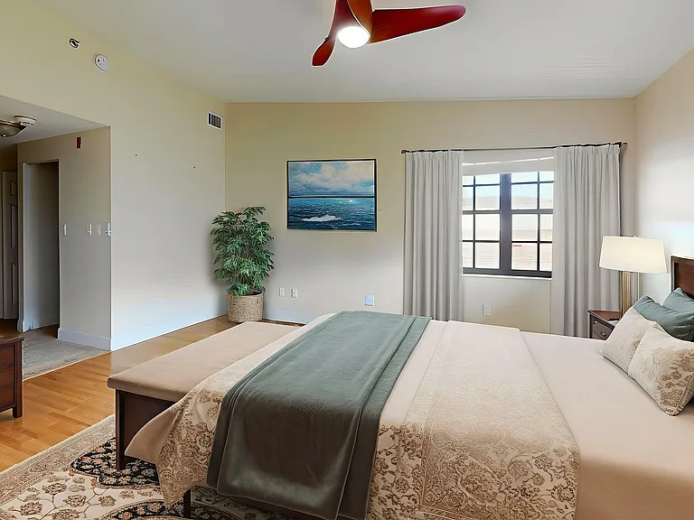 Elegant bedroom with a luxurious king-size bed, modern fan lighting, and a scenic window view. Features stylish decor, a flat-screen TV, and a cozy ambiance.