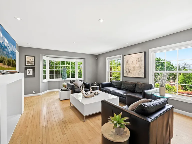 Main living room with tons of windows, built in shelving, and cozy fireplace.