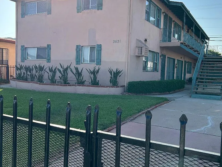 front of the building with green lawn , flowers and front gate