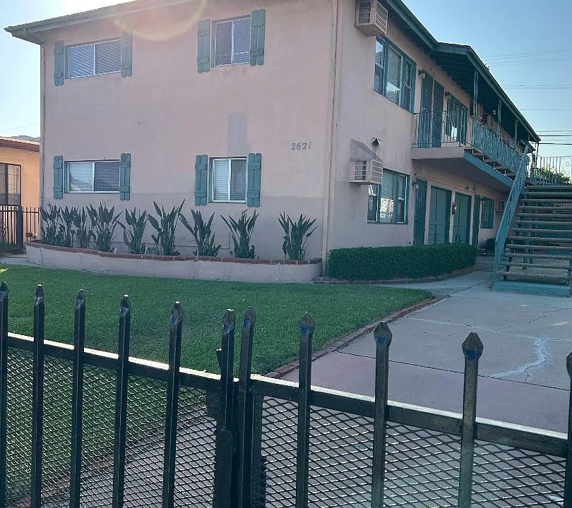 front of the building with green lawn , flowers and front gate