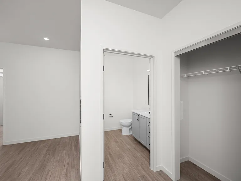 Elegant modern apartment featuring a bright hallway, a pristine bathroom with sleek fixtures, and a spacious walk-in closet with open shelving. Elegant modern apartment featuring a bright hallway, a pristine bathroom with sleek fixtures, and a spacious wa
