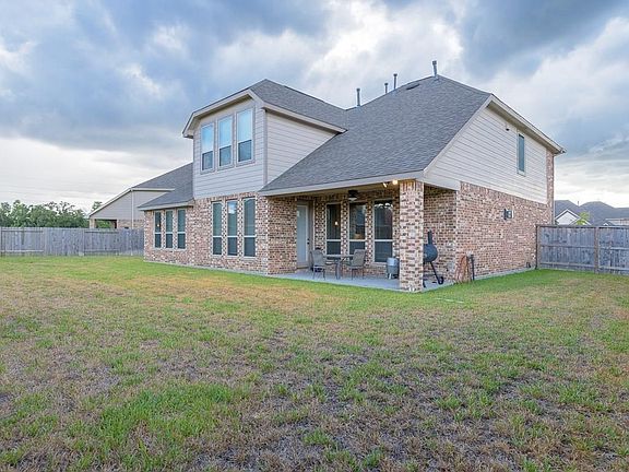 This view shows the back of the home with covered patio and plenty of room for kids and pets to run.