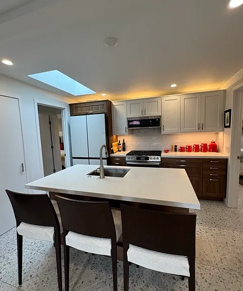 Kitchen and breakfast bar. Includes Samsung Bespoke series refrigerator / freezer with white panel front. Includes 4 compartments, Beverage Center and 2 sizes of ice. 4th compartment can be refrigerator or freezer.