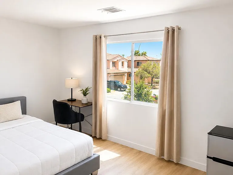 Private bedroom with a large window, wood-look flooring, a work desk, and space for a mini fridge, walk in closet