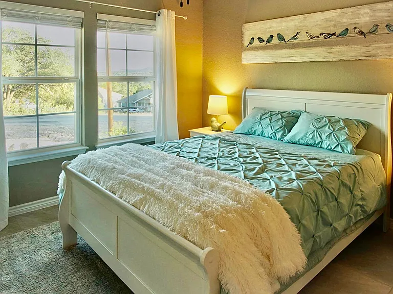 Guest bedroom includes a spacious closet, ceiling fan, and large windows that let in plenty of natural light.