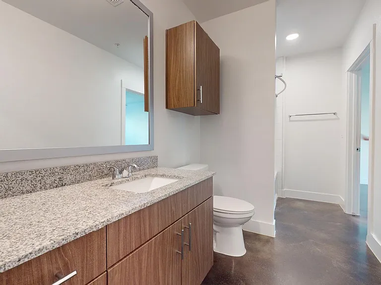 Apartment bathroom with large soaking tub and polished concrete flooring.