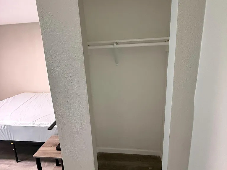 Bedroom closet nook with hanging rod and shelf, offering convenient in-room storage for clothing and personal items.