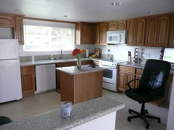 Kitchen view from living/dining room area. Partial open concept. Appliances replaced with similar. (please note, prior tenant's content items in photo not included with home)
