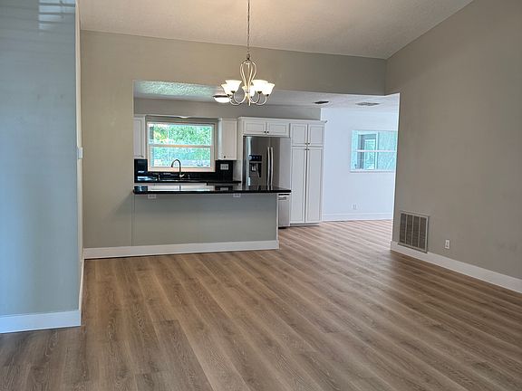 Family room, kitchen. Flooring is showing darker than it actually is