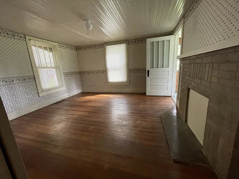 Original hardwoods in the office / hobby room. External door opens to a glassed-in porch.
