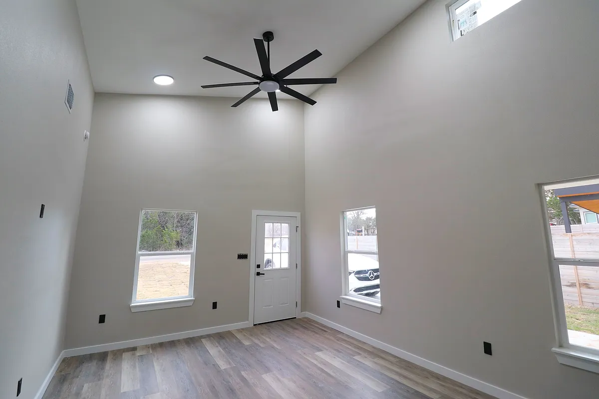 Bright open-concept living area with high ceilings, modern ceiling fan, and abundant natural light. Clean finishes and spacious layout. - 3600 Ottawa Dr