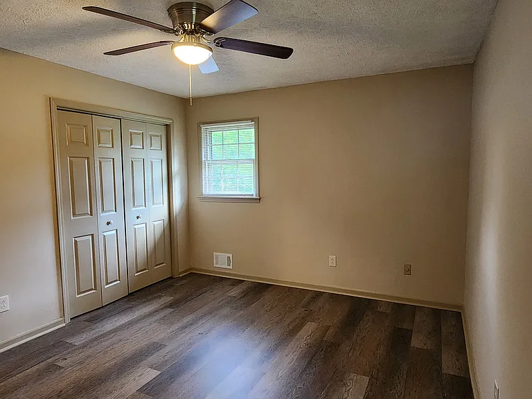 Master bedroom with double-door closet and ceiling fan.