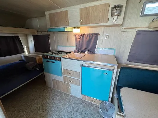 Compact kitchenette with upper cabinetry, gas cooktop, sink, and built-in mini fridge for convenient daily meal prep.