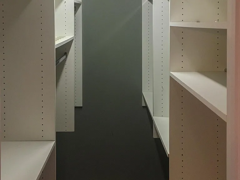 Master bedroom walk in closet with wood floor.