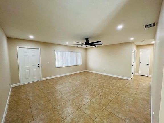 Large tiled living room with ceiling fan.