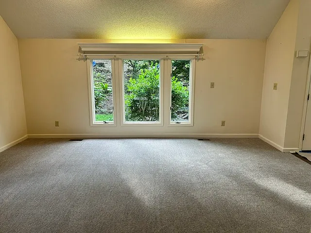 Front room with dramatic vaulted celling and large windows inviting all the natural light one would desire