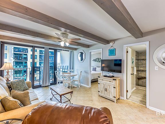 Living room with light tile patterned flooring, beamed ceiling, and ceiling fan