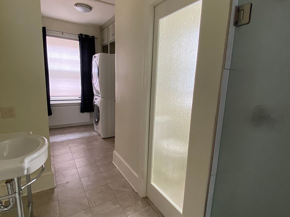 Hallway area with stacked laundry unit, toilet, basin and shower