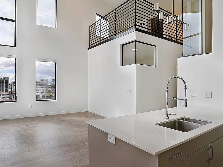 Double-height living space with modern kitchen design in a Greenside penthouse.