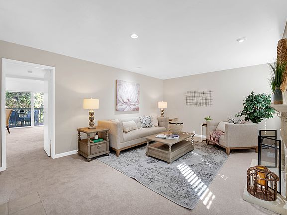 Large living area with fireplace, recessed lighting, and large windows that look on to private paved patio.