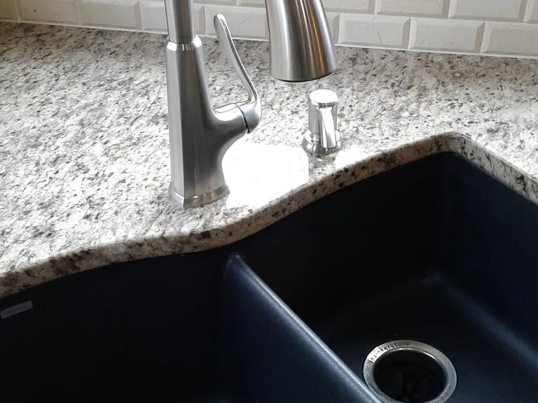 Stainless steel faucet with black granite sink.