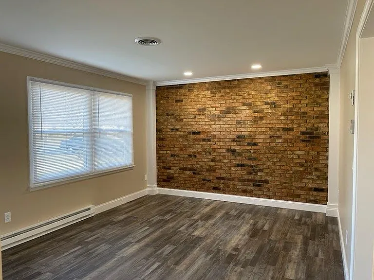 Exposed brick wall with custom columns, crown moulding and 5 1/4" baseboards.